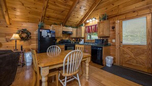 L’intérieur d’un chalet en bois comprend une table à manger, des chaises, un réfrigérateur, un four à micro-ondes et une porte en bois.