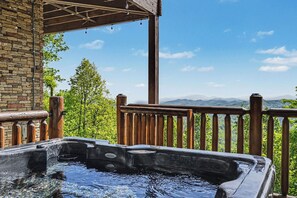 A hot tub with a wooden deck and a mountain view.
