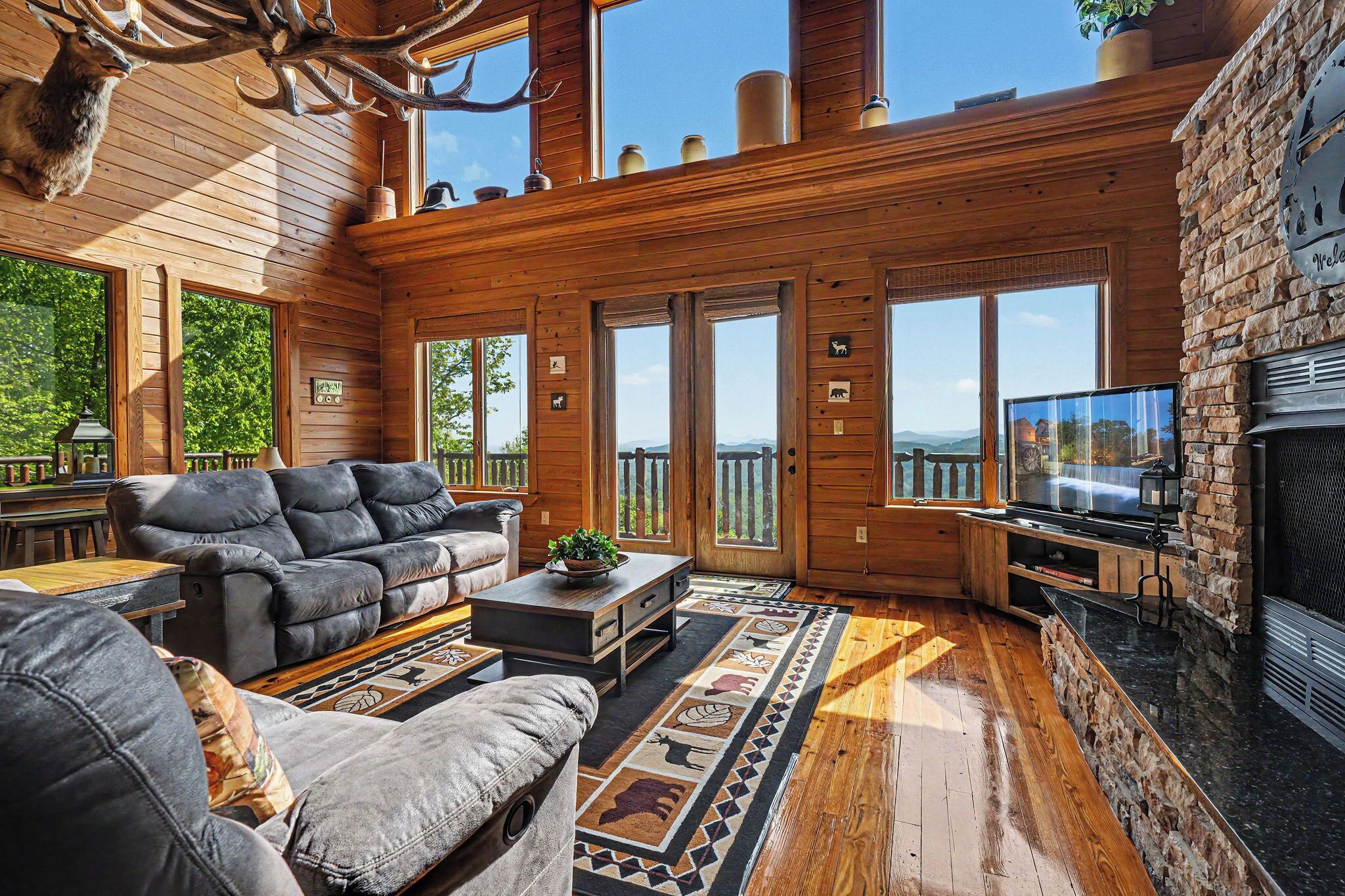 A spacious living room with a fireplace, leather sofas, and a large TV.