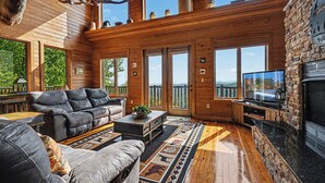 A spacious living room with a fireplace, leather sofas, and a large TV.