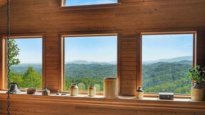 A wooden cabin with large windows overlooking a mountainous landscape.