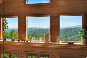 A wooden cabin with large windows overlooking a mountainous landscape.