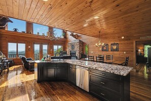 A spacious kitchen with a large island, wooden ceiling, and a stone fireplace. - Incredible Mountain Views*Unique Property (PIGEON FORGE)
