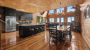 A spacious kitchen with a central island, wooden floors, and a large dining area with a chandelier.