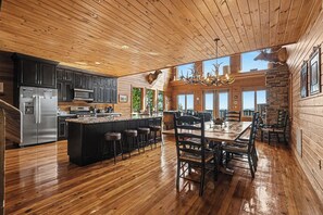 A spacious kitchen with a central island, wooden floors, and a large dining area with a chandelier.