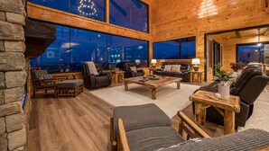 A spacious living room with wooden floors and large windows, furnished with leather sofas and armchairs, and a central coffee table. - Outdoor Games, Indoor Games, Incredible Views (SEVIERVILLE)