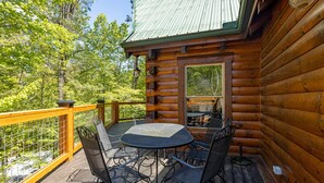 A wooden cabin with a deck, a round table, and four chairs. - Large Living Area| Game Room| Secluded| Easy Access (SEVIERVILLE)