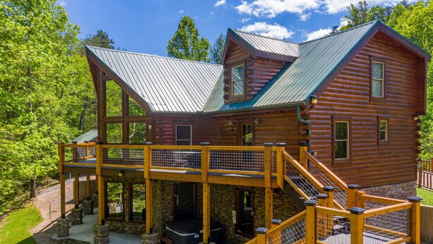 A log cabin with a covered porch, a hot tub, and a stone fireplace. - Large Living Area| Game Room| Secluded| Easy Access (SEVIERVILLE)