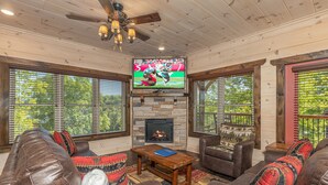 A cozy living room with leather sofas, a fireplace, and a television displaying a sports game. - Pigeon Forge*Resort*Dogs Welcome*Sleeps 12*Dollywood (SEVIERVILLE)
