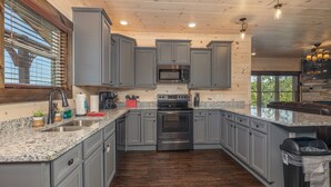 A kitchen with grey cabinets, a stainless steel oven, granite countertops, and a wooden floor. - Pigeon Forge*Resort*Dogs Welcome*Sleeps 12*Dollywood (SEVIERVILLE)