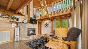 Ein gemütliches Blockhaus-Interieur mit Kamin, Holzmöbeln und einem Balkon.