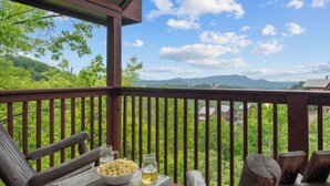 Eine Holzterrasse mit Blick auf grüne Hügel und Berge.