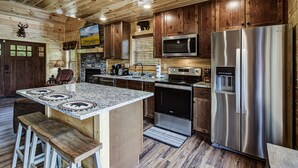 Eine moderne Küche mit Holzschränken, Edelstahlgeräten und einer Arbeitsplatte aus Granit.