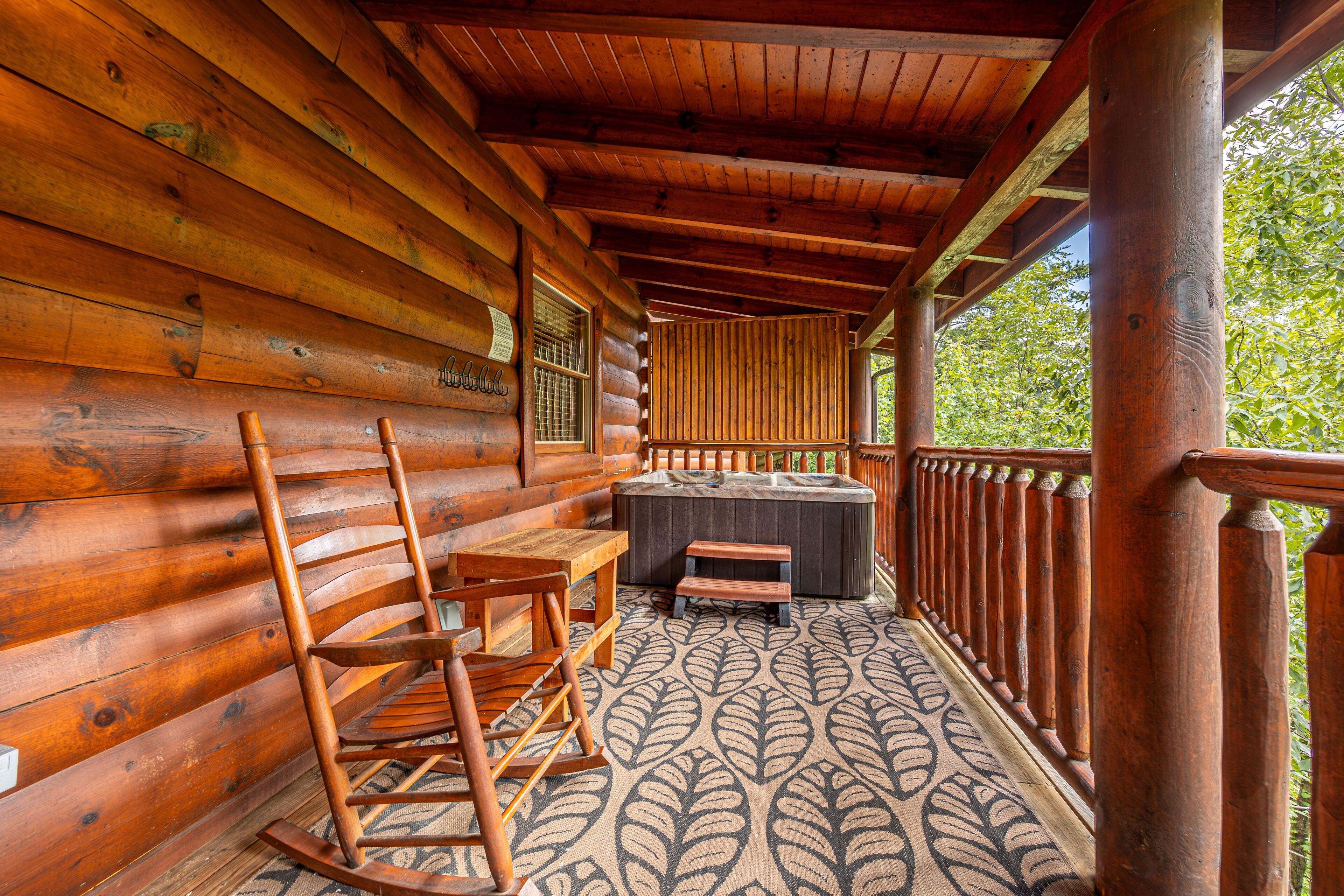 A wooden log cabin with a rocking chair, a table, and a hot tub.
