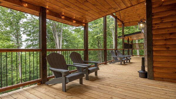 A wooden deck with Adirondack chairs and a lantern.