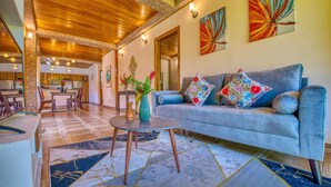 Una sala de estar moderna con un sofá azul, almohadones coloridos, una mesa redonda y un jarrón con flores.