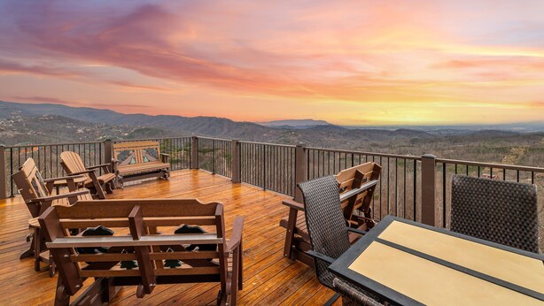 Eine Holzterrasse mit Gartenmöbeln, die einen weiten Panoramablick auf die Landschaft bietet.