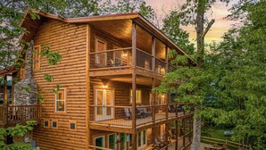 Eine mehrstöckige Blockhütte mit Balkon, Sitzgelegenheit im Freien und Whirlpool.