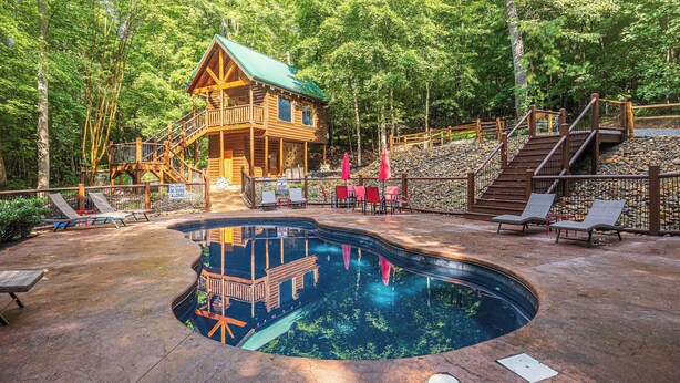 Eine Holzhütte mit Pool, umgeben von Bäumen.