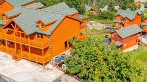 A cluster of log cabin-style buildings with green roofs, surrounded by lush greenery and hills in the background. - Mountain Views And Games Galore (SEVIERVILLE)