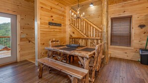 A wooden interior with a dining table, benches, a chandelier, a staircase, and a window with blinds. - Mountain Views And Games Galore (SEVIERVILLE)