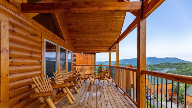 A wooden deck with log walls, outdoor seating, and a view of mountains. - Mountain Views And Games Galore (SEVIERVILLE)