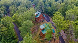A large wooden cabin with a green roof surrounded by dense forest, accessible by a winding road. - Private Pool*Awesome Views of the Strip*Game Room*Hot tub (GATLINBURG)