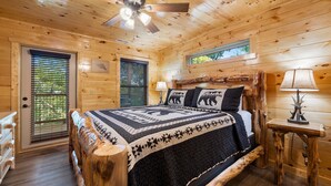 Ein Schlafzimmer einer Holzhütte mit einem Bett, einem Deckenventilator, einem Fenster und einer Tür.