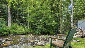 A wooden bench by a stream in a forested area with a small shed in the background. - Near The Golf Corse, On The Creek (COSBY)