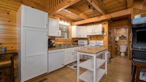 A compact kitchen with white cabinetry, a built-in microwave, a stove, and a sink. - Easy Access, Outdoor Games, Open Skies (SEVIERVILLE)