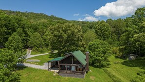 A cabin with a green roof, surrounded by lush greenery and a clear sky. - Easy Access, Outdoor Games, Open Skies (SEVIERVILLE)