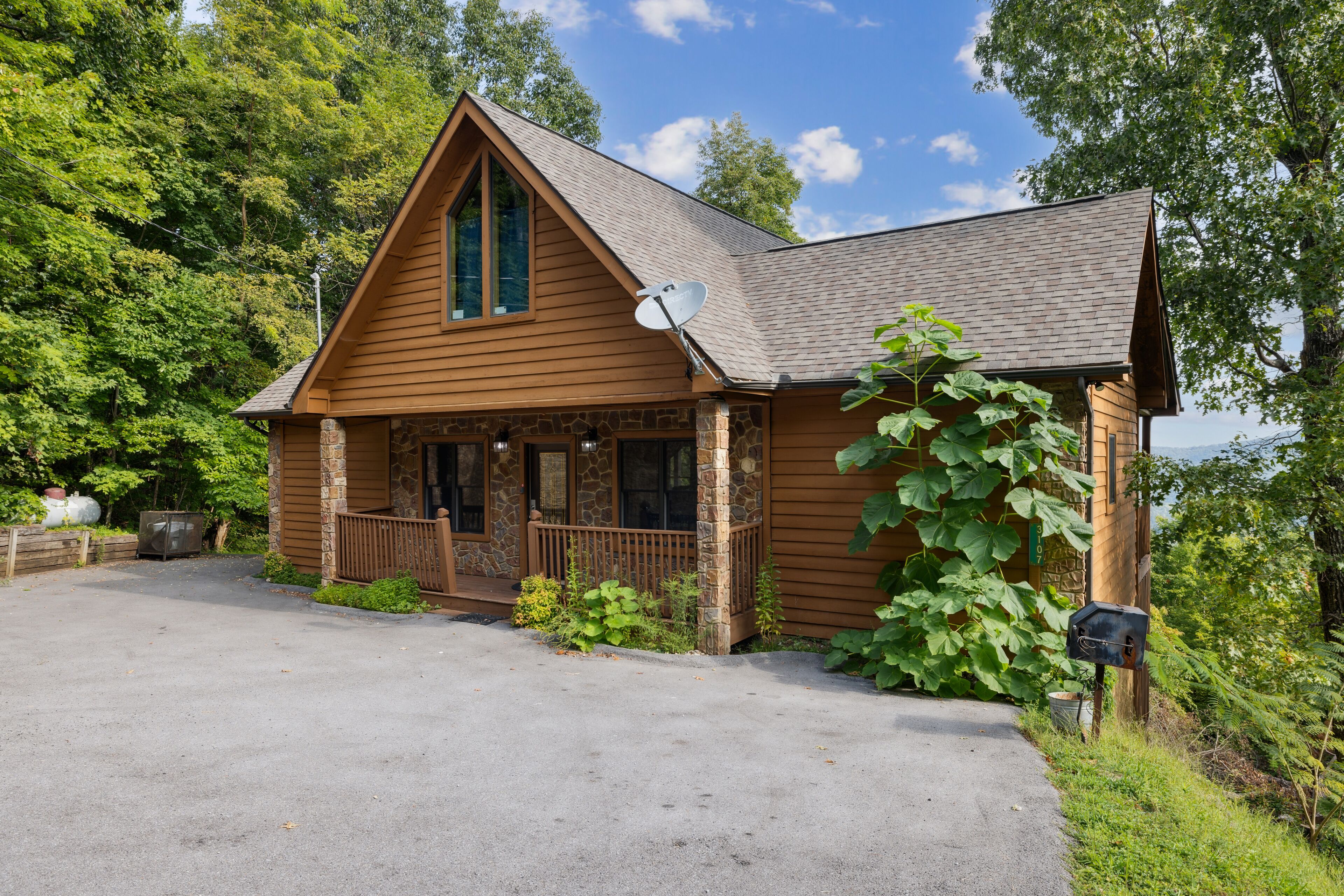 Een houten chalet met een stenen fundering, een veranda en een schotelantenne.