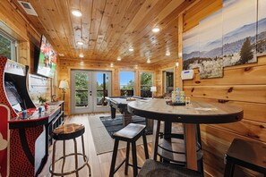 Een houten interieur met een pooltafel, een bar en kunstwerken aan de muren.