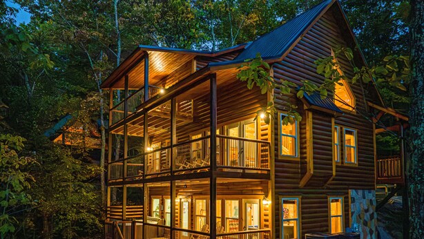 A multi-story log cabin with a balcony, surrounded by trees. - Experience Exclusivity: Unwind at Moonrise Pool Lodge Luxury Cabin (SEVIERVILLE)