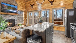 A log cabin interior with a stone fireplace, wooden ceiling, and deer antlers decoration. - Experience Exclusivity: Unwind at Moonrise Pool Lodge Luxury Cabin (SEVIERVILLE)