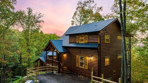 A log cabin with a metal roof, a porch, and a fenced driveway. - Experience Exclusivity: Unwind at Moonrise Pool Lodge Luxury Cabin (SEVIERVILLE)