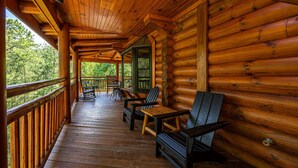 Eine Holzhütte mit Veranda, ausgestattet mit Holzstühlen und Tischen.