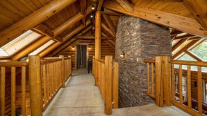 Ein Holzinnenraum mit Kamin aus Stein, Holzgeländern und einer hohen Decke mit Dachfenstern.