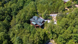 Eine Vogelperspektive zeigt eine Hütte, umgeben von dichtem Wald.