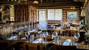 Un restaurante rústico con interiores de madera, una zona de bar y mesas dispuestas para comer.