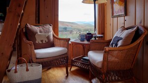 Una habitación acogedora con sillones de mimbre, una mesa con lámpara y vistas al campo.