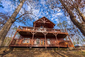 A wooden cabin with a balcony and a porch, surrounded by trees. - Give In To Your Wild Side The Smoky Mountain Way (SEVIERVILLE)