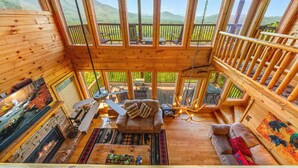 A wooden cabin with a loft bedroom, a fireplace, and a balcony with a scenic mountain view. - 1 Awesome View - Secluded Cabin In Pigeon Forge (PIGEON FORGE)