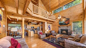 A spacious log cabin interior with a high ceiling, a fireplace, a dining area, and a cozy seating area. - 1 Awesome View - Secluded Cabin In Pigeon Forge (PIGEON FORGE)