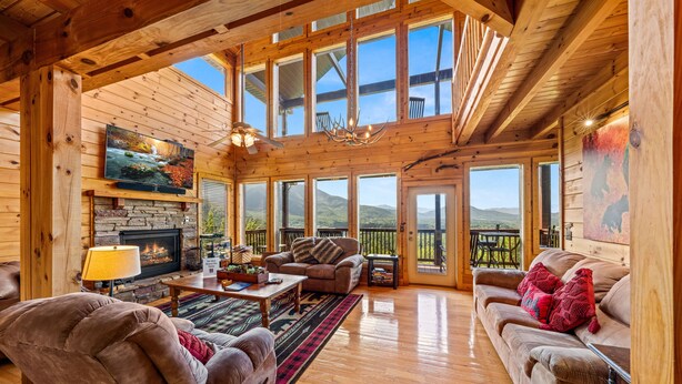 A spacious wooden cabin interior with a fireplace, comfortable seating, and large windows offering mountain views. - 1 Awesome View - Secluded Cabin In Pigeon Forge (PIGEON FORGE)