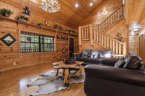 Een houten interieur met een trap, een bank, een tafel en decoratieve objecten.