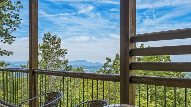 A wooden deck with a hot tub, chairs, and a view of mountains and greenery. - 4 States View-Gatlinburg, Private Pool, Game Room (GATLINBURG)
