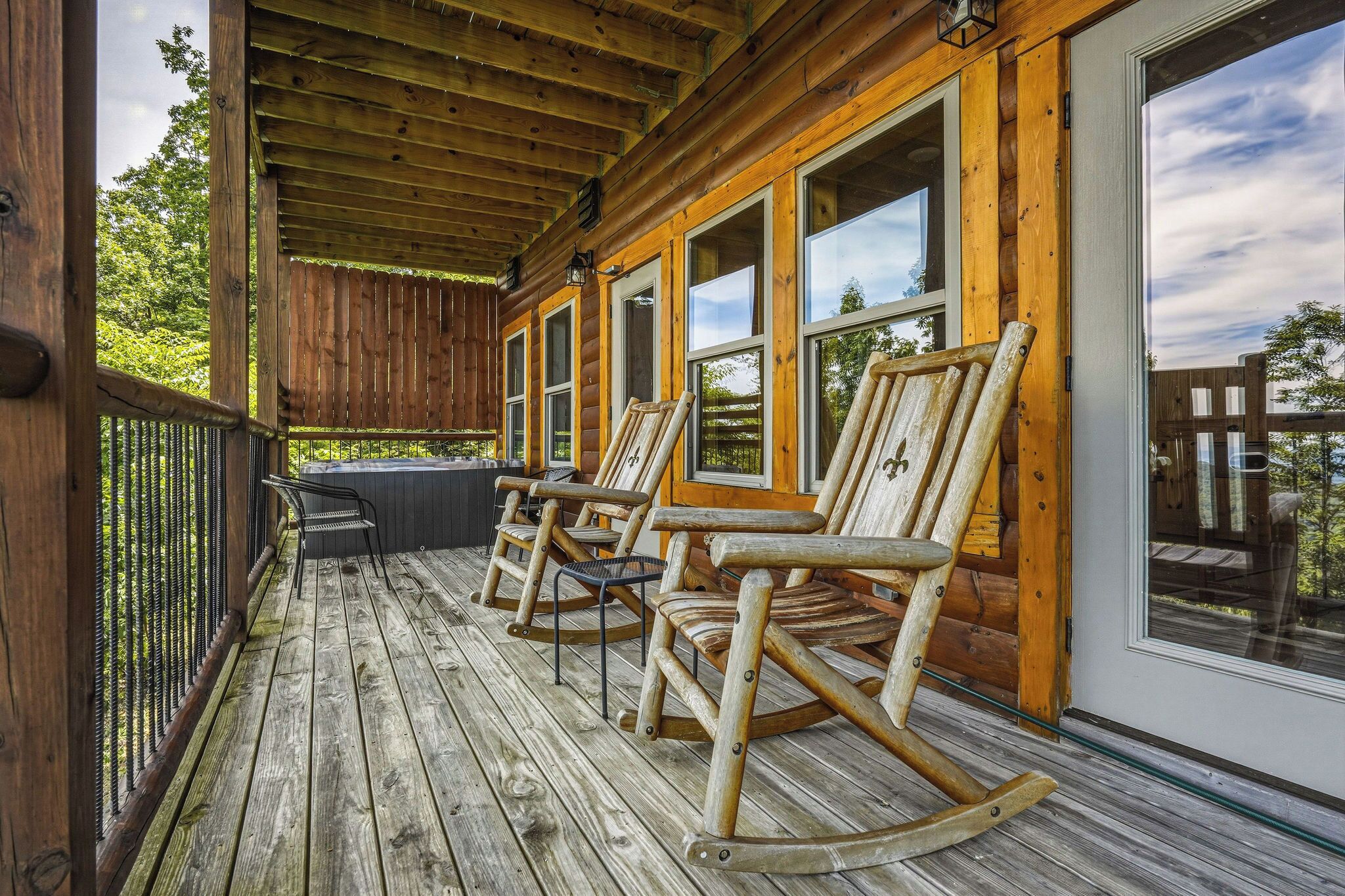 A wooden porch with rocking chairs and a glass door.