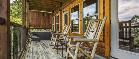 A wooden porch with rocking chairs and a glass door.