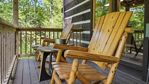 Una terraza de madera con dos sillas Adirondack y una mesita.